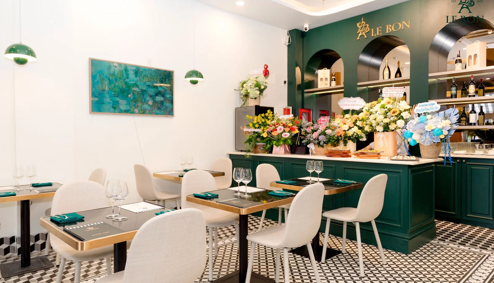 Le Bon interior — Parisian-style bistro with emerald green cabinetry, arched wine display, Monet painting, and checkered tile floor in Da Nang